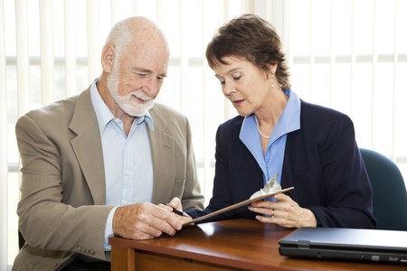 Senior man signing a contract in his attorney's office.  の写真素材