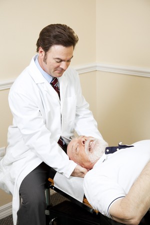 Chiropractor treats a senior man for neck pain.  の写真素材