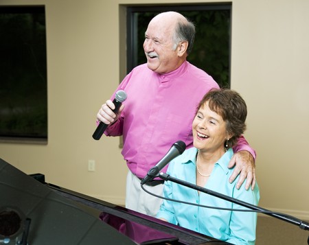 Senior couple performing a song together.  She plays piano.  の写真素材
