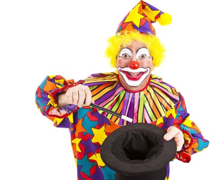 Cheerful birthday clown does a magic trick with a want and top hat.  Isolated on white.  