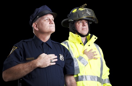 Police officer and fire fighter with their hands over their hearts as they say the Pledge of Allegiance.  の写真素材