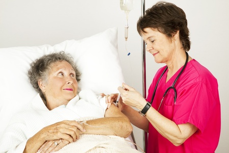 Hospital nurse giving an elderly female patient an injection in her arm.  の写真素材