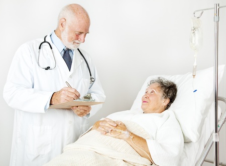 Doctor reviews his hospital patient's medical history, taking notes.  の写真素材