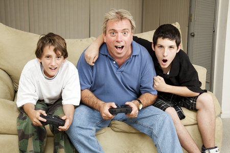 Uncle playing video games with his nephews.  Could also be dad and sons.  の写真素材