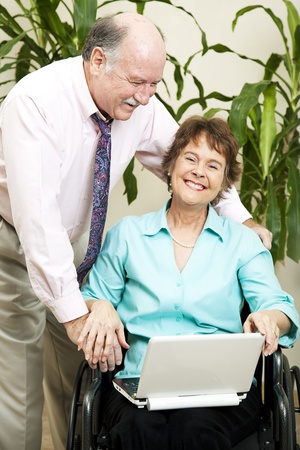 Disabled businesswoman and her boss laughing together as they surf the internet.  の写真素材