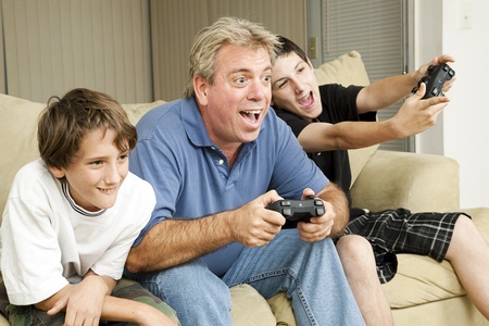 Uncle and his two nephews playing video games together.  Could also be father and sons.  の写真素材