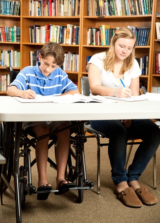 Disabled boy and a friend doing homework in the school library.の写真素材