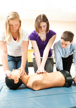 Two teenage girls and a boy practicing CPR life saving in school.  の写真素材