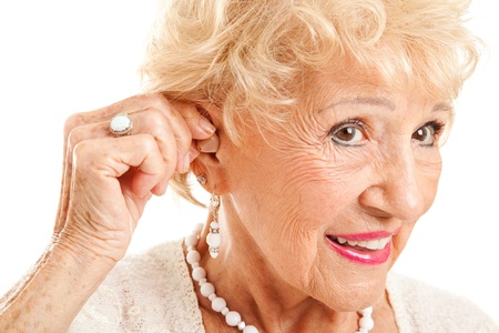 Closeup of a senior woman inserting a hearing aid in her hear.  Focus on the hearing aid.  の写真素材