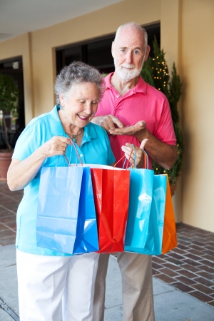 Senior couple shopping. She's happy with her purchases, and he's upset because she spent all his money.  の写真素材
