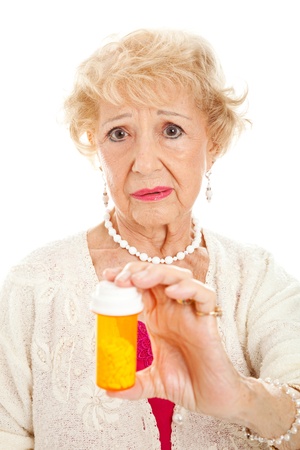 Sad senior woman holding a bottle of pills.  White background.の写真素材
