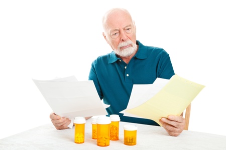 Senior man depressed by a pile of medical bills.  Isolated on white.  の写真素材