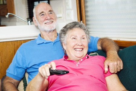 Senior couple watching television in their small traveling motor home.  の写真素材