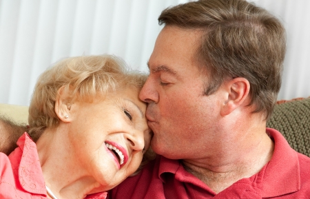 Adult man kissing his elderly mother on the forehead.  Closeup portrait.の写真素材