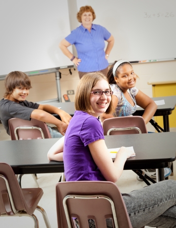 Portrait of teenage students and their teacher in the classroom.  Focus on the girl in the front with glasses.の写真素材