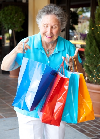 Senior woman smiles as she looks into her shopping bags to check out what sheの写真素材