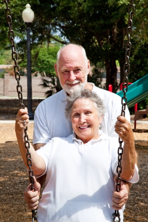Romantic senior husband pushing his lovely wife in a swing on a playground   の写真素材