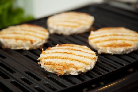 Healthy low fat turkey burgers cooking on the grill  の写真素材