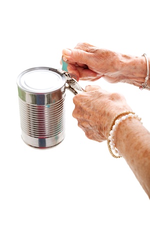 Closeup of elderly hands, with arthritis, struggling to use a can opener.  Isolated on white.  の写真素材