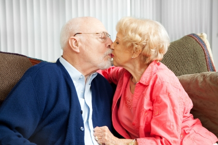 Senior couple in love, kissing on the couch.  の写真素材