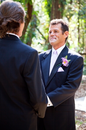 Handsome hispanic groom marrying his same sex partner in an outdoor wedding ceremony.  の写真素材
