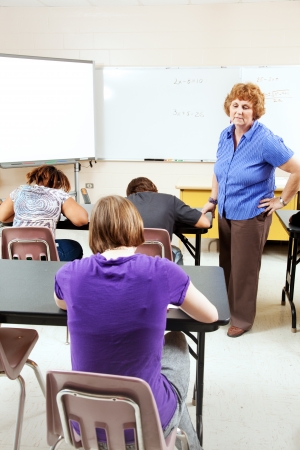 Female teacher monitoring a test in high school setting.  の写真素材