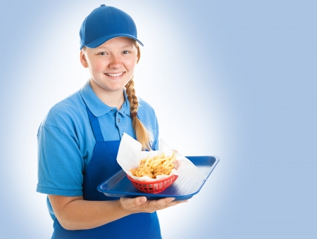 Teenage fast food worker holding a tray of chicken nuggets and fries. Blue backgroundの写真素材