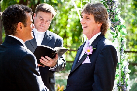 Handsome groom looks lovingly into his partner's eyes during their wedding ceremony.  の写真素材