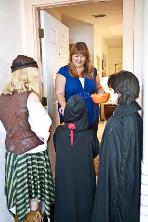 Friendly home owner passing out Halloween candy to neighborhood trick-or-treating children.  の写真素材