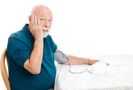 Senior man taking his blood pressure and shocked by the results.  White background.の写真素材