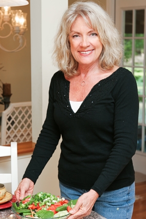 Beautiful, healthy and fit mature woman serving a fresh green salad   の写真素材