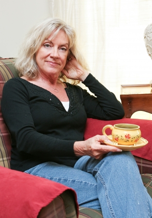 Beautiful mature blond woman relaxing at home with a cup of coffee or tea   の写真素材