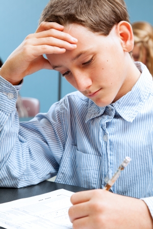 Cute adolescent school boy concentrates while taking a standardized test   の写真素材