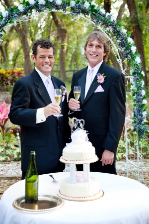 Handsome gay couple toasting with champagne at their beautiful outdoor wedding reception. の写真素材