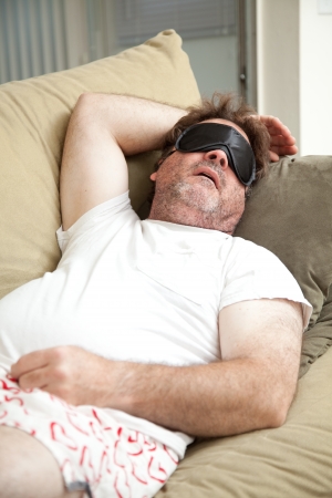 Lazy, unemployed man asleep on the couch, unshaven and in his underwear.  の写真素材