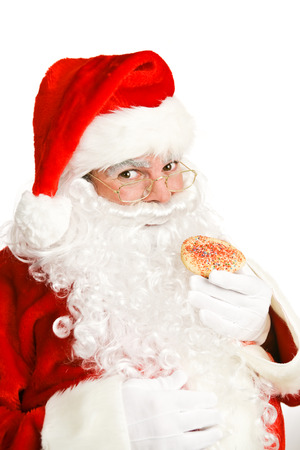 Cheerful Santa Claus eating a Christmas cookie.  White background.  の写真素材