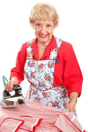 Beautiful senior lady doing her ironing.  Isolated on white.  の写真素材