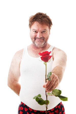 Scruffy looking man in his underwear holding out a single red rose for his sweetheart.  Isolated on white.  の写真素材