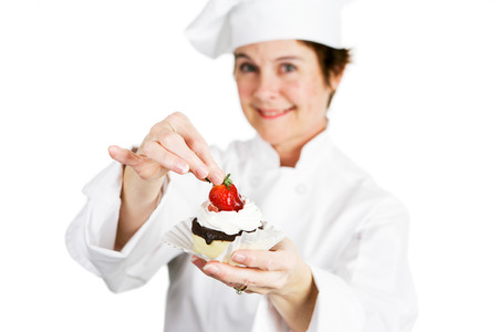 Closeup of a pretty baker holding a delicious strawberry chocolate cheesecake tart.  Shallow depth of field with focus on the strawberry and the tart.の写真素材