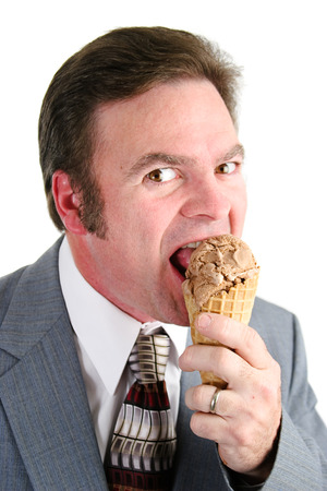Handsome caucasian businessman eating a chocolate ice cream waffle cone.  Isolated on white background.  の写真素材
