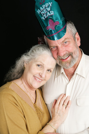 Beautiful couple in their sixties posing for a romantic portrait on New Year's Eve.  Black background.の写真素材