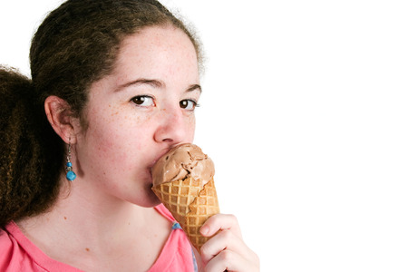 Pretty young hispanic girl eating a chocolate ice cream waffle cone.  Closeup isolated on white with copyspace.の写真素材