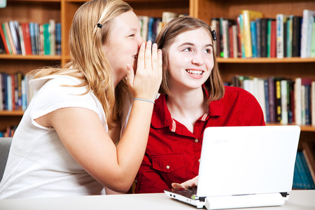School girls whispering in the library.の写真素材