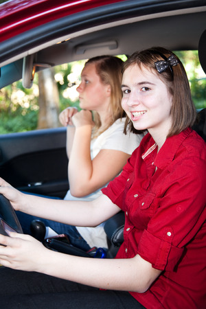 Teenage girl driving with a friend in the passenger seat.の写真素材