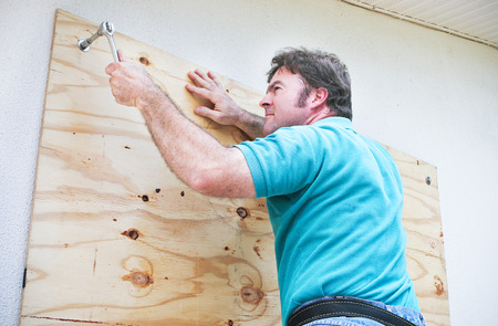 Man boarding up the windows on his home to prepare for a hurricane or tornado.の写真素材