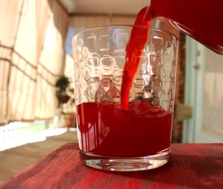 Pouring Red Fruit Drink into Glass Outsideの写真素材