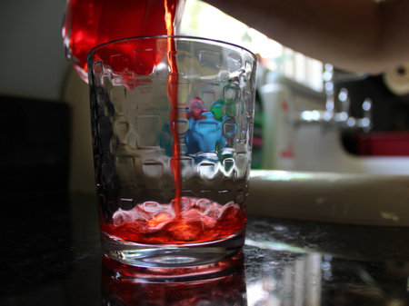 Sunlight on Red Drink Pouring into Glassの写真素材