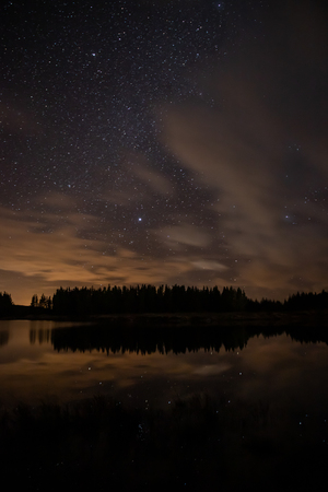 Night sky with starts in a  Conemara lake with Pine Forest around, Maam Cross, Galway, Irelandの写真素材