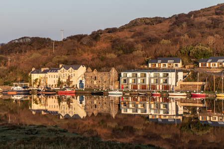 Pier and buildings reflected in Clifden bay, Clifden, Galway, Conemara, Irelandの写真素材