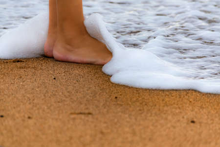 sea wave covering feet on the beach shoreの写真素材